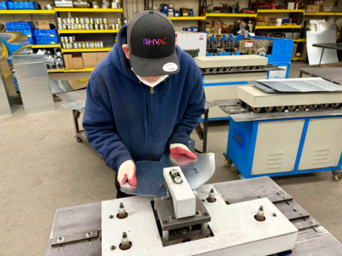 Worker inspecting fabricated duct components during quality control